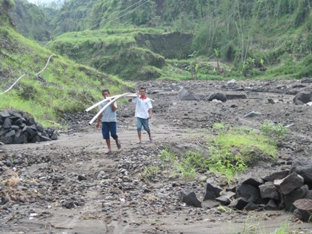 ANGKUT PIPA RUSAK—Dua orang warga Desa Klakah, Selo mengangkut pipa rusak yang diterjang banjir lahar dingin di Kali Apu, Selasa (11/1). (FOTO: Espos/Ahmad Mufid Aryono)
