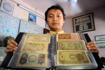 KOLEKSI BERHARGA -- Eko AGus Purnom menunjukkan koleksi uang kuno miliknya, yang juga dipajang di toko uang kunonya di Jalan Museum, Sriwedari, Solo. (JIBI/SOLOPOS/Dwi Prasetya)