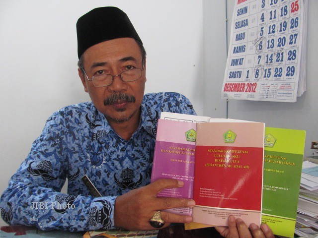 Kepala Seksi Penamas dan PK Pontren Kemenag Solo, Maulud Munif, memperlihatkan beberapa buku berisi kurikulum, standar kompetensi dan standar kelulusan madrasah diniah, Senin (17/12), di ruang Seksi Penamas dan PK Pontren Kemenag Solo. (FOTO/Istimewa)