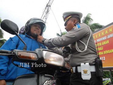 Kasatlantas Polres Klaten, AKP Kurniawan Ismail,memasangkan helm gratis yang diberikan kepada salah satu pengendara bermotor yang tertib berlalu lintas. Pemberian helm gratis ditu dilakukan dalam operasi simpatik yang digelar oleh Satlantas Polres Klaten di Jl Pemuda, tepatnya di depan alun-alun Klaten, Senin (13/5/2013). (JIBI/SOLOPOS/Shoqib Angriawan) 