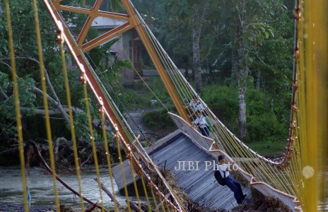 Pelajar SLTP meniti jembatan gantung yang rusak di Sungai Pinjauan, Nagari Pilubang, Padangpariaman, Sumbar, Rabu (8/1). Jembatan gantung yang dibangun pada 2013 itu rusak akibat diterjang luapan sungai sehingga menyebabkan akses dua desa terputus. ANTARA FOTO/Iggoy el Fitra