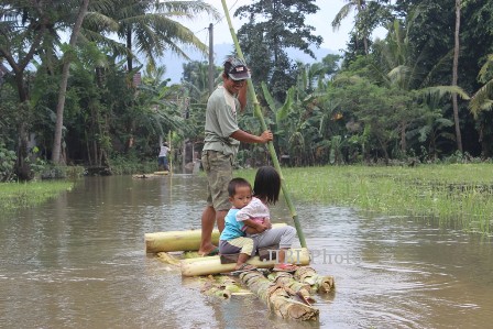 Warga menaiki getek bersama dua orang anaknya untuk menyeberangi jalan yang tergenang banjir di warga Dusun Muker, Desa Melikan, Kecamatan Wedi, Senin (24/2/2014). (ilustrasi/JIBI/Solopos/Shoqib Angriawan)