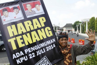 Mulyoto, 56, membawa poster saat melakukan aksi damai di depan Balai Kota Solo, Senin (21/7). Aksi tersebut menghimbau warga supaya tenang dalam menanggapi hasil Pilpres 2014 yang akan diumumkan oleh KPU pada Selasa (22/7/2014). (JIBI/Solopos/Adiansyah Indra Kumala