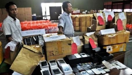 Polisi berpakaian preman berdiri di dekat sejumlah barang bukti ponsel pintar replika dan rekondisi ilegal, saat gelar perkara di Ditreskrimsus Polda Jateng, di Semarang, Kamis (16/1/2014).(JIBI/Solopos/Antara/R. Rekotomo)
