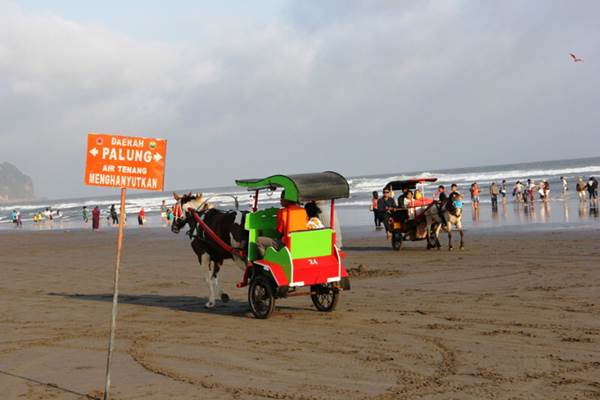 Wisatawan Papan pengumuman penunjuk lokasi palung Pantai Parangtritis sebagai himbauan agar wisatawan tidak berenang di Pantai Parangtritis seperti terlihat pada foto yang diambil, Sabtu (18/7/2015).(JIBI/Harian Jogja/Joko Nugroho)saat menikmati libur Lebaran hari pertama di Pantai Parangtritis, Sabtu (18/7/2015). (JIBI/Harian Jogja/Joko Nugroho)