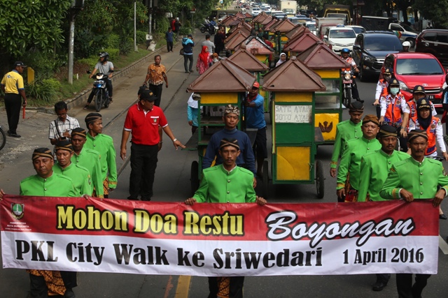 Pedagang kaki lima (PKL) mendorong gerobak saat mengikuti kirab Boyongan PKL Citywalk di Jl. Slamet Riyadi, Solo, Jumat (1/4/2016). Kirab boyongan tersebut diikuti 55 PKL yang direlokasi dari citywalk, Jl. Slamet Riyadi ke kawasan sisi selatan dan timur Stadion Sriwedari. (Ivanovich Aldino/JIBI/Solopos)