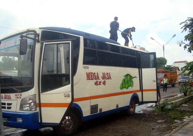 Dua orang petugas pemadam kebakaran menyeprotkan air ke cerobong AC di bagian atas Minibus Mega Jasa yang terbakar di Jl. Sragen-Ngawi Desa Banaran, Kecamatan Sambungmacan, Sragen, Senin (18/4/2016). (Tri Rahayu/JIBI/Solopos)