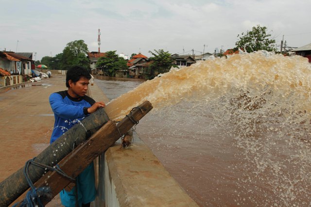 Seorang petugas menguras air banjir dengan mesin pompa yang membanjiri pemukiman tepi Sungai Ciliwung, Kampung Pulo, Jakarta Timur, Kamis (21/4/2016). Hujan deras yang mengguyur kawasan Jabodetabek sejak malam hingga pagi hari mengakibatkan banjir di beberapa pemukiman tepi sungai di Jakarta. (JIBI/Solopos/Antara/Regina Safri)