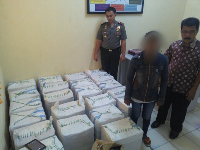 Pelaku penjual miras ciu,LS,37, (tengah) saat dibawa ke Mapolsek Banjarsari brrsama Kapolsek Banjarsari Kompol Danu Pamungkas (kiri). (Aries Susanto/JIBI/Solopos)