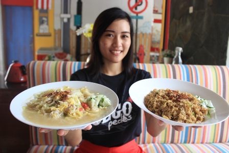 Salah satu karyawati Sego Pedes Restoran, Rosiani M, menunjukkan menu bakmie godok dan nasi goreng jowo yang ditawarkan di resto setempat, Kamis (21/4/2016). (Shoqib Angriawan/JIBI/solopos)