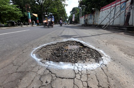 Warga melintasi jalan berlubang yang tergenang air hujan di Jl. Bhayangkara, Solo, Kamis (7/4/2016). (Ivanovich Aldino/JIBI/Solopos)