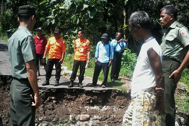 Warga dan anggota Koramil Kawedanan melihat lokasi jembatan jebol yang menghubungkan antara Desa Banjarejo dan Desa Selorejo di wilayah Kawedanan, Magetan. (Istimewa)