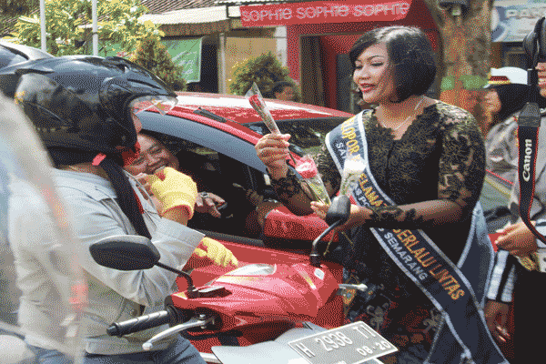 Salah satu wanita polisi atau polwan Polres Semarang tengah membagikan bunga dan memberi pengarahan tentang keselamatan berlalu lintas pada salah satu pengguna jalan di pertigaan Jl Pemuda, Ungaran, Kabupaten Semarang, Kamis (21/4/2016). (Imam Yuda Saputra/JIBI/Semarangpos.com)