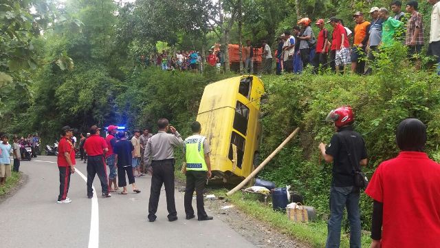 Warga mengevakuasi mobil angkudes yang terguling di tanjakan jalan raya Dukuh Tumpuk, Ponorogo, Jumat (8/4/2016). (Istimewa)