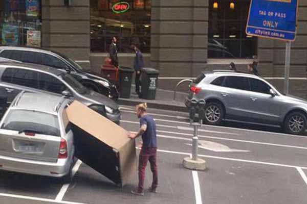 Seorang pria memasukan mebel berukuran besar ke dalam mobil kecil (Dailymail)