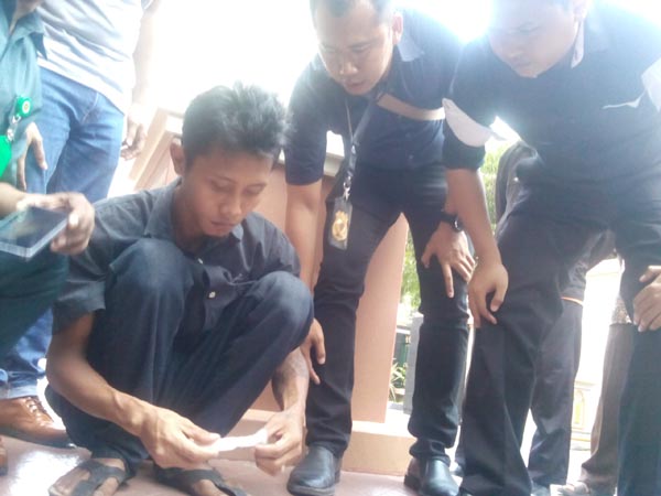 Seorang pengunjung sidang, Ricky Ferdian (jongkok kiri) membuka bungkusan bawaannya yang diduga sabu dalam bungkus rokok di teras Gedung PN Sleman, Selasa (5/4/2016). (Sunartono/JIBI/Harian Jogja)