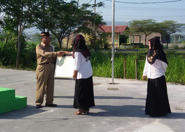 Kepala Dinas Pendidikan Menengah dan Nonformal (Dikmenof) Kabupaten Bantul, Masharun Ghozali saat menyerahkan piagam penghargaan Ujian Nasional berintegritas kepada SMK Ki Ageng Pemanahan yang diterima oleh Kepala Sekolah Wresti Eka Triyuliani, Senin (18/4/2016). (Foto istimewa)