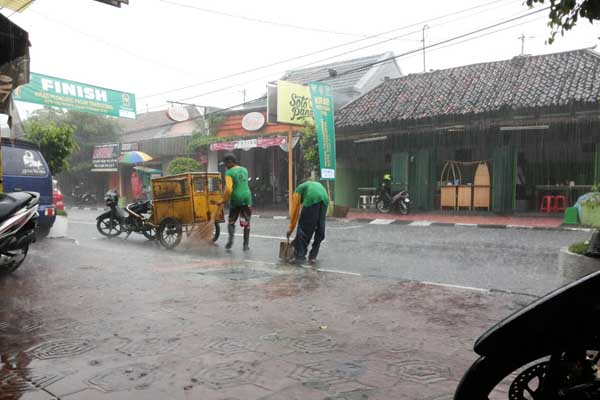 Dua petugas kebersihan menyapu jalan Ngasem di bawah guyuran hujan, Kamis (13/10/2016) siang. (Mayang Nova Lestari/JIBI/Harian Jogja)