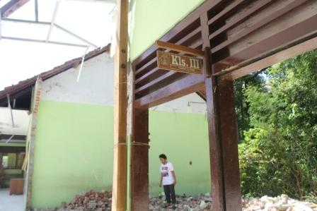 Seorang warga melihat puing-puing reruntuhan dua ruang kelas SD Negeri 02 Tugurejo yang dirobohkan karena rusak akibat bencana tanah gerak, Senin (26/12/2016). (Abdul Jalil/JIBI/Madiunpos.com)