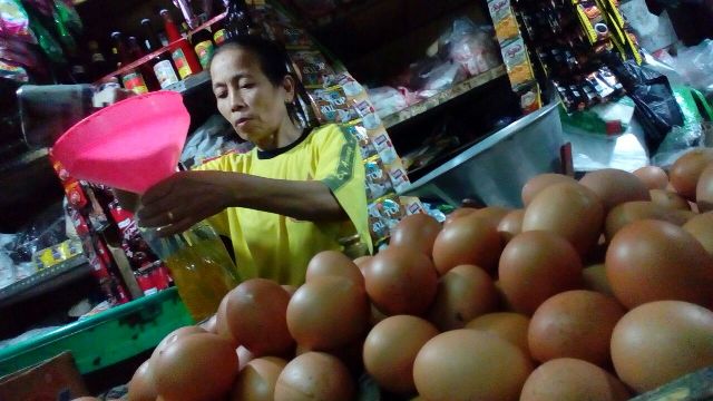 Seorang pedagang kebutuhan pokok di Pasar Songgolangit Ponorogo mengemasi minyak goreng curah, Jumat (23/12/2016). (Abdul Jalil/JIBI/Madiunpos.com)