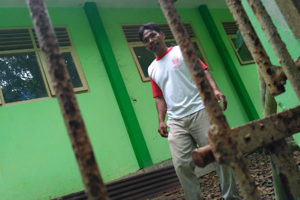 Penjaga SMP Negeri 3 Pleret saat hendak memeriksa pintu pagar besi yang dibuka paksa oleh pencuri, Senin (26/12/2016). (Arief Junianto/JIBI/Harian Jogja)
