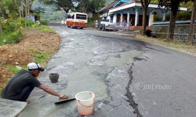 Seorang warga menambal jalan raya Ponorogo-Pacitan, Desa Wates, Kecamatan Slahung, Ponorogo, yang merekah lantaran terdampak tanah gerak, Senin (20/2/2017). (Istimewa)