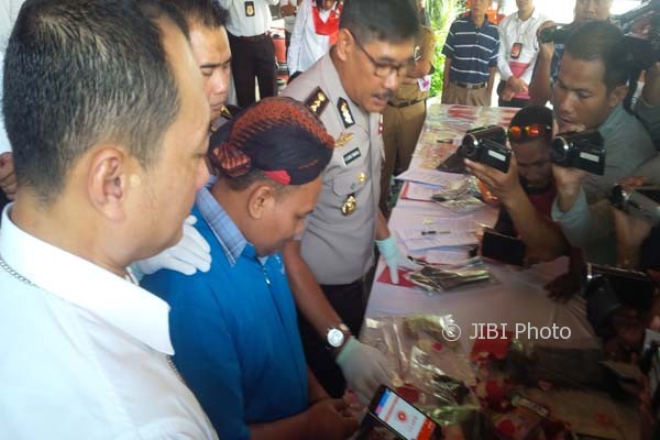 Tersangka kasus penipuan dengan cara menggandakan uang, Muhammad Rifa’i Adi Nugroho (baju biru), tengah menunjukkan uang palsu yang digunakan mengelabuhi korbannya kepada aparat polisi di Mapolda Jateng, Semarang, Senin (20/3/2017). (JIBI/Semarangpos.com/Imam Yuda Saputra)