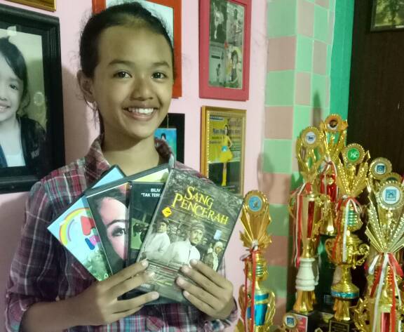 Shava Shava berfoto dengan menunjukkan film-film yang dibintanginya.