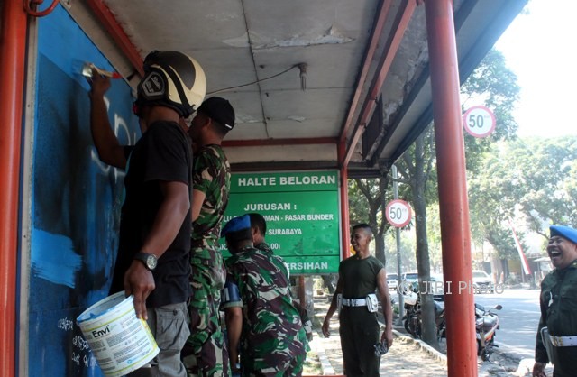 Polisi militer bersama warga bergotong-toyong mengecat dan menutup tulisan vandalisme di halte angkutan umum di Kampung Beloran, Sragen Kulon, Sragen, Rabu (17/5/2017). (Tri Rahayu/JIBI/Solopos)