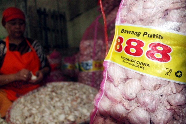 Seorang buruh sibuk mengupas kulit bawang putih impor jenis kating di Pasar Bunder Sragen, Sabtu (13/5/2017). (Tri Rahayu/JIBI/Solopos)