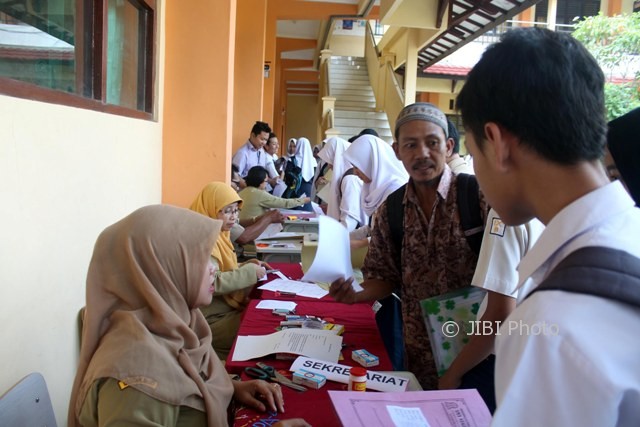 Pendaftar menyodorkan berkas pendaftaran PPDB online kepada petugas di SMAN 1 Sragen, Senin (12/6/2017). Setelah berkas diterima, para calon siswa baru menuju ke loket verifikasi dan kemudian ke loket entry data. (Tri Rahayu/JIBI/Solopos)