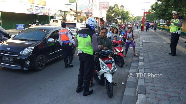 Petugas tim gabungan menegur orang tua yang mengantar anak sekolah tanpa menggunakan helm di Jl. Letjen Sutoyo, Kelurahan Nusukan, Banjarsari, Solo, Senin (31/7/2017) pagi. (Istimewa/dokumen Dishub Solo)