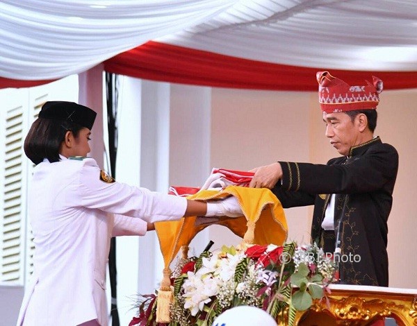Presiden Joko Widodo mengambil bendera dari pembawa baki, Ruth Celine Eglesya Purba, saat Upacara Penurunan Bendera, Kamis (17/8/2017) di Istana Merdeka. (Facebook)