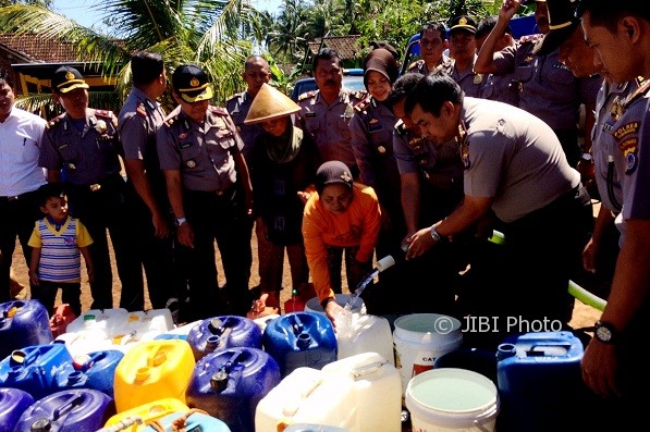 Kepala Polres Gunungkidul AKPB Muhammad Arif Sugiarto (pegang selang) saat memasukan bantuan air bersih ke dalam jeriken milik warga Dusun Ngricik, Desa Melikan, Rongkop, Senin (27/7/2017). (David Kurniawan/JIBI/Harian Jogja)