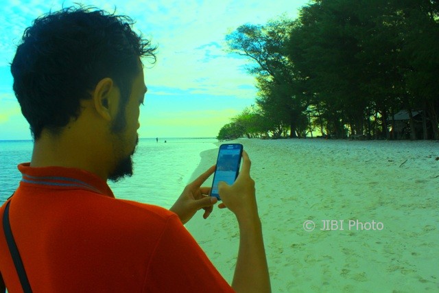Wisawatan menggunakan gadget untuk browsing dengan jaringan 4G dari Telkomsel di Pulau Cemara Kecil, Karimunjawa, Jepara, Jawa Tengah, Selasa (8/8/2017). (Abdul Jalil/JIBI/Solopos.com)
