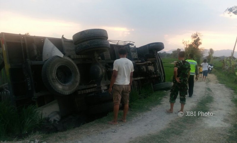 Petugas melihat truk fuso yang mengangkut lima batang tiang listrik terguling di areal persawahan di Desa Sukorejo, Ponorogo, Jumat (6/10/2017). (Istimewa/Polres Ponorogo)