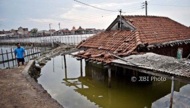 Warga melintasi rumah yang ditinggal pemiliknya akibat terendam rob di Kampung Tambakrejo, Tanjung Emas, Kota Semarang, Jateng, Rabu (4/10/2017). (JIBI/Solopos/Antara/Aditya Pradana Putra)