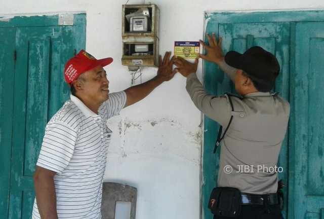 Seorang anggota Babinkamtibmas Polsek Mojolaban Sukoharjo memasang striker di rumah penduduk, Selasa (3/10/2017). (Istimewa/Humas Polres Sukoharjo)