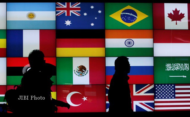 Sejumlah awak media melintas di depan layar dengan gambar bendera-bendera negara G-20 di Seoul, Korea Selatan, 2013 lalu. Saat itu, dunia menyambut G-20 Summit di
St Petersburg, Rusia, Kamis-Jumat (5-6/9/2013). (JIBI/Solopos/Reuters/Jo Yon-Hak)