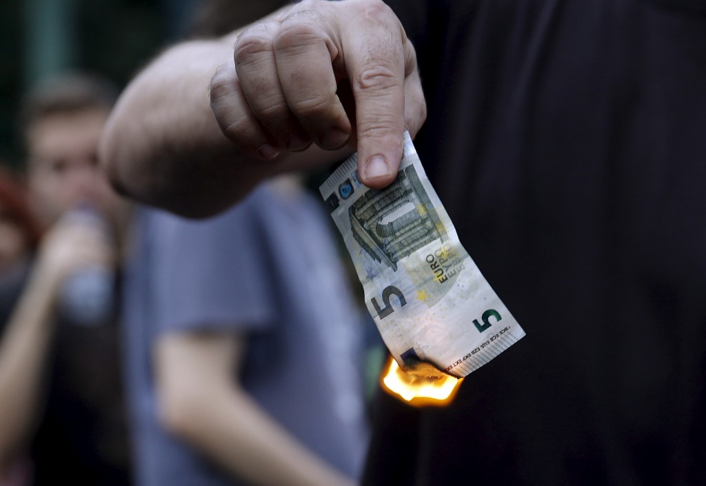 Demonstran anti pengetatan keuangan Yunani membakar selembar uang euro di luar Kantor Perwakilan Uni Eropa, Athena, Yunani, Minggu (18/6/2015). (JIBI/Solopos/Reuters/Alkis Konstantinidis)