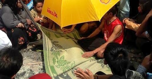 Jasad Ahmad Rafli, 9, yang tewas terserempet KA Sancaka di perlintasan Jl. Juwingan, Ngagel, Surabaya dibungkus tikar (Detik.com/Imam Wahyudiyanta)