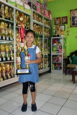 Elvaretta Cicelyana Yocelyn, 10, berdiri dengan membawa piala juara I nasional dengan latar belakang ratusan pialanya di rumahnya, di Perumahan Margoasri Gang 12 RT 036/RW 009, Puro, Karangmalang, Sragen, Kamis (7/5/2020). (Tri Rahayu/Solopos)