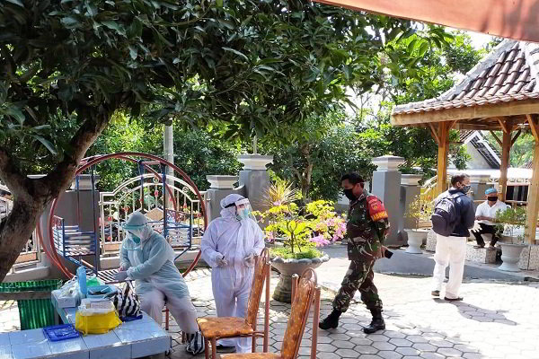 Tim nakes DKK dengan pengamanan dari personel TNI/Polri melakukan tracing terhadap warga yang kontak erat dengan pasien Covid-19 di wilayah Desa Wonorejo, Kedawung, Sragen, Senin (8/6/2020). (Istimewa)