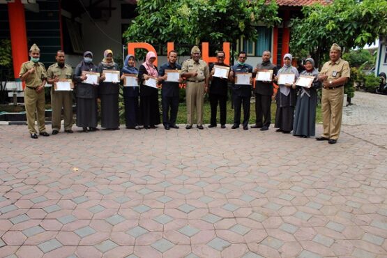 Sebanyak 11 perwakilan sekolah memperlihatkan ijazah Sekolah Adiwiyata tingkat Kabupaten Sragen saat berfoto bersama dengan petugas di Kantor DLH Sragen, Senin (12/10/2020). (Solopos.com-Tri Rahayu)