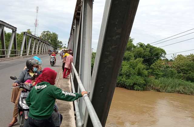 Warga berkerumun di tepi Jembatan Sapen untuk menyaksikan lokasi warga diduga menceburkan diri ke Sungai Bengawan Solo, Jumat (4/12/2020). (Solopos-Moh. Khodiq Duhri)