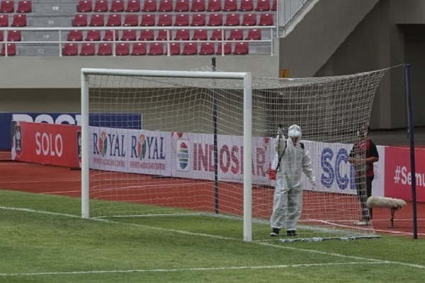 Petugas menyemprotkan cairan disinfektan ke jarring di salah satu gawang di lapangan Stadion Manahan, Solo, sebelum pertandingan Piala Menpora 2021, Minggu (21/3/2021). (Solopos.com/Nicolous Irawan)