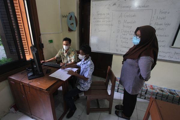 Calon peserta didik baru dibantu guru saat memasukkan data pada pendaftaran Penerimaan Peserta Didik Baru (PPDB) online 2021 tingkat SMP melalui jalur zonasi di SMP Negeri 4, Solo, Rabu (23/6/2021). (Solopos/Nicolous Irawan)