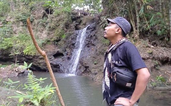 Sekretaris Desa (Sekdes) Krikilan, Sragen, Aries Rustioko, berfoto dengan latar belakang air terjun di sekitar Situs Sangiran.