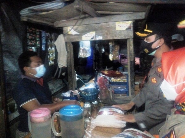 Kapolres Grobogan AKBP Benny Setyowadi didampingi Kepala Pelaksana BPBD Grobogan Endang Sulistyoningsih membagikan paket sembako kepada PKL angkringan di dekat Stadion Purwodadi, Sabtu (23/7/2021) malam. (Solopos.com/Arif Fajar S.)