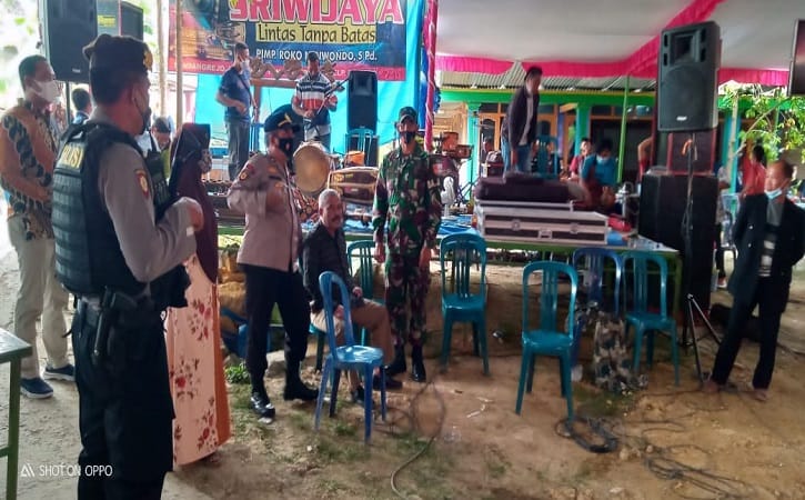 Petugas TNI dan Polri berusaha meredam emosi Kades Jenar, Kecamatan Jenar, Sragen, Samto, setelah mendorong meja sebagai bentuk protes acara hajatan warga dibubarkan, Jumat (16/7/2021). (Istimewa/Satgas Covid-19 Kecamatan Jenar)